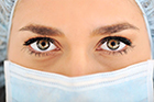 A close-up photo of a women wearing a surgical mask